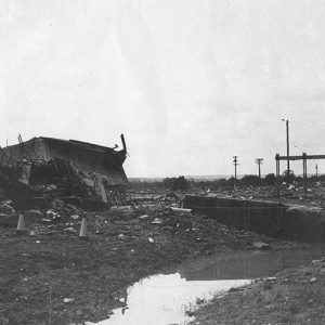 Debris covered field with telephone poles in the background