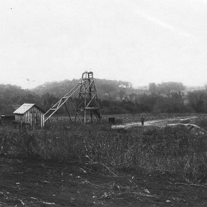 Wooden structure and cabins with smokestack in field