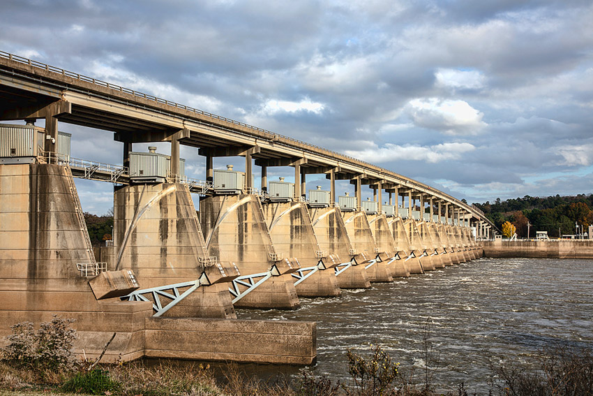 Side view of concrete dam topped by bridge