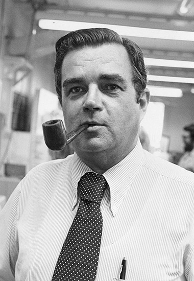 White man in shirt and tie smoking a pipe