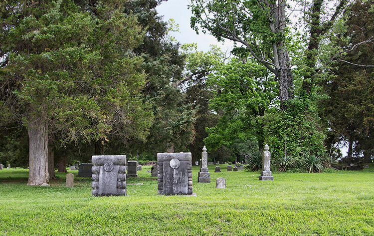 Gravestones and monuments under trees in cemetery