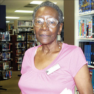 Old African-American woman with glasses in pink shirt in library
