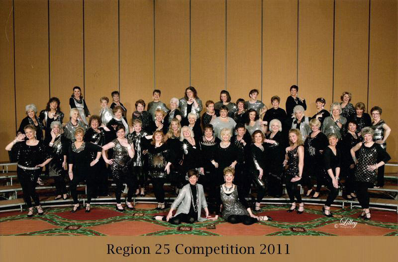 Group of white women in black and sparkly silver dress clothes standing and posing on risers