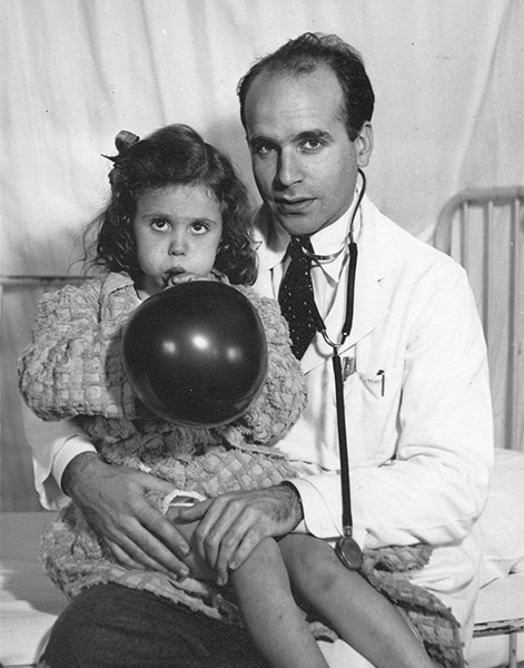 White male doctor with young white girl blowing up a balloon