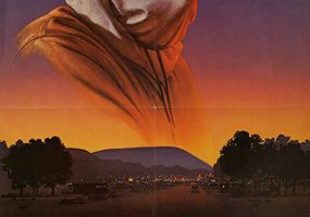 Man in hood with eye holes and town on movie poster