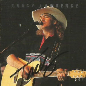 White man in cowboy hat singing and playing an acoustic guitar on concert advertisement