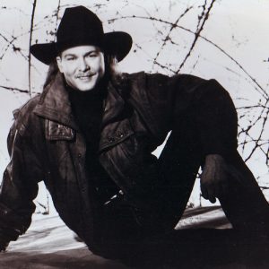 Young white man with mustache posing in cowboy hat and jacket