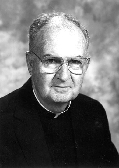 Old white man with glasses wearing black clerical outfit with white collar