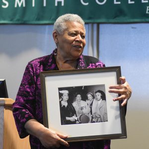 Old African-American woman smiling while holding a framed photograph