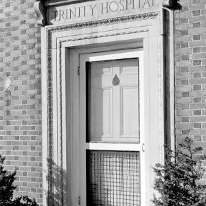 Door on brick wall with "Trinity Hospital" written above it
