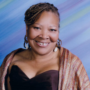 African-American woman smiling in sleeveless top and multicolored shawl
