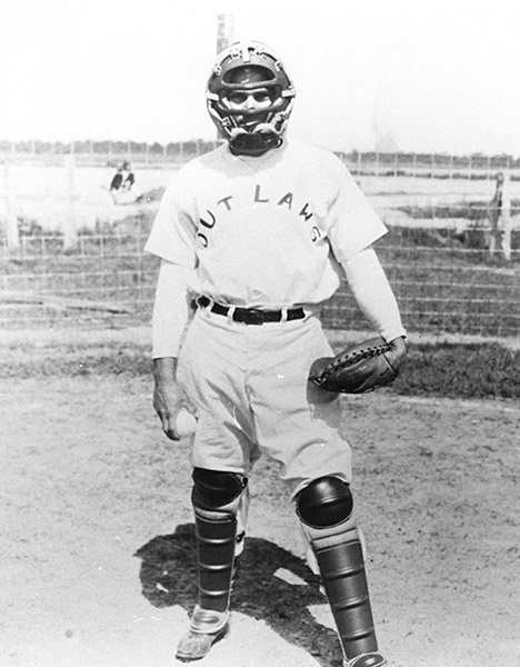 White man in catcher's uniform with glove and ball