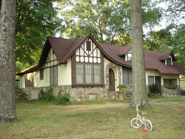 Two-story Tudor house with stone foundation and trees