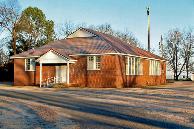 Single-story red brick building with ramp leading to small covered front porch