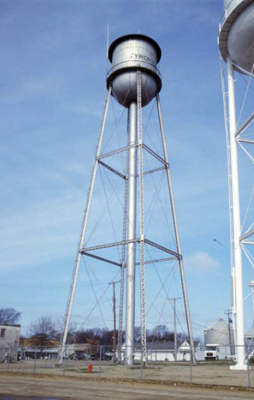 Two water towers and buildings inside fence