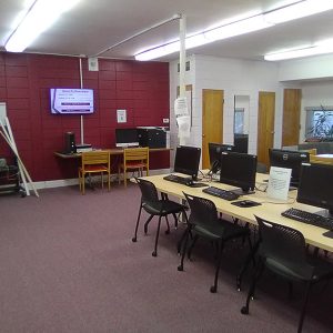 Classroom with computers on table in center and couch in background