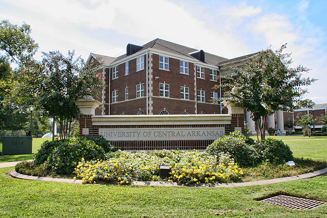 brick sign reading "University of Central Arkansas" in front of three-story brick building