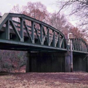 Side view of steel arch bridge over river with concrete supporting columns
