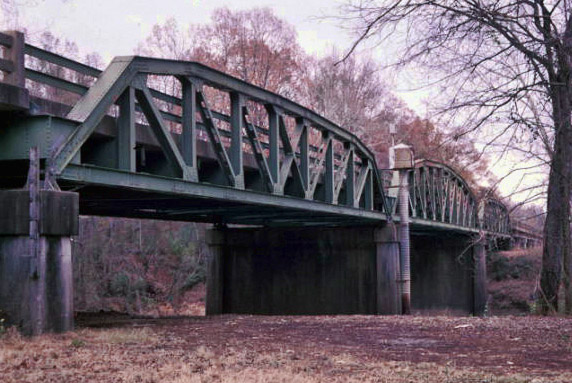 Side view of steel arch bridge over river with concrete supporting columns