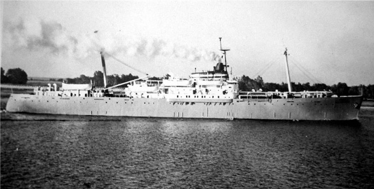 Side view of long ship underway with shore in the background