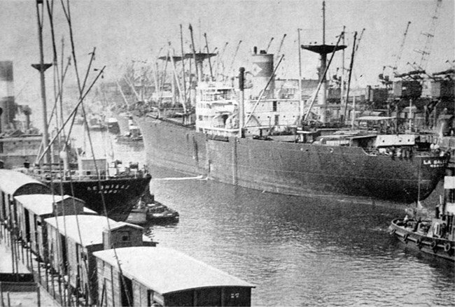 Ships at port with buildings and tugboat in the foreground