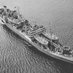 Aerial view of naval ship underway at sea with four boats on deck