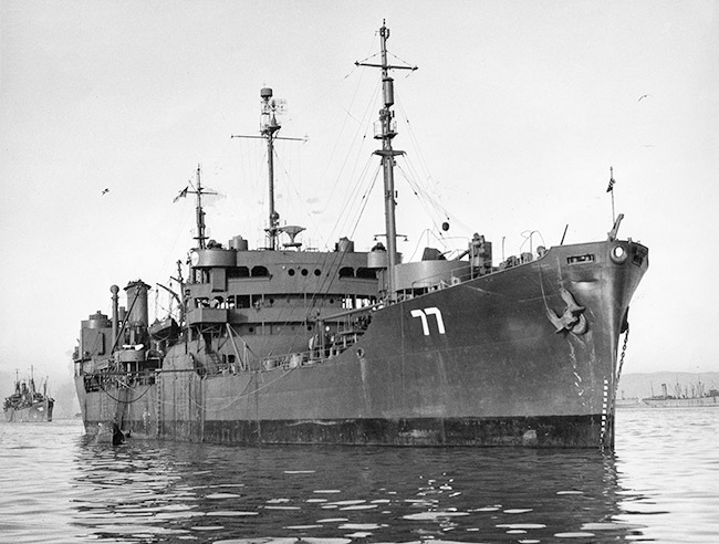 Close-up of naval ship at sea with number 77 on its bow and similar ship behind it in the background