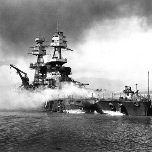 Small boat putting out fire on deck of battleship at sea