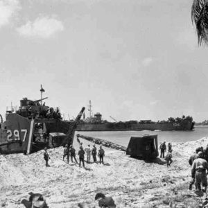 Cranes being unloaded from beached Naval vessel by soldiers with large ships in the background
