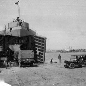 Military vehicles being loaded onto Naval vessel from a barge