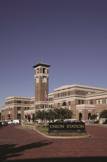 large multistory brick train station with arched entrances and tall bell tower