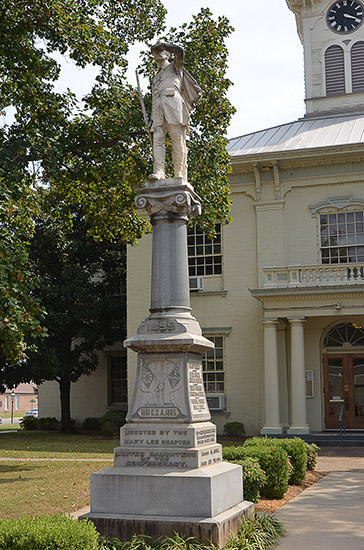 Statue of soldier on stone column with engraved pedestal on court house lawn
