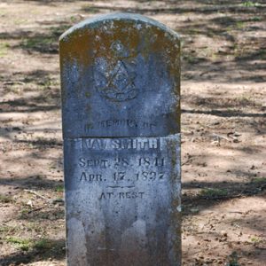 Weathered stone marker with Masonic symbol in cemetery