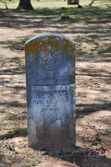Weathered stone marker with Masonic symbol in cemetery