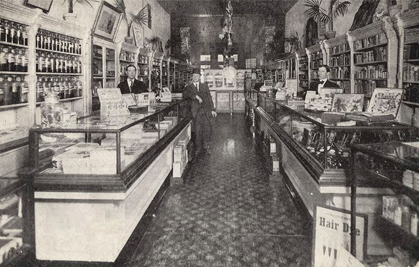 Three white men standing in store with display counters