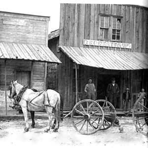 People standing on porch or wooden storefront behind horse and buggy