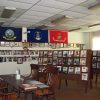 Wall covered in flags and framed photographs with reading table and chairs