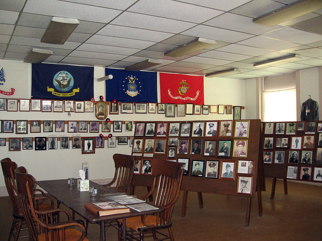 Wall covered in flags and framed photographs with reading table and chairs