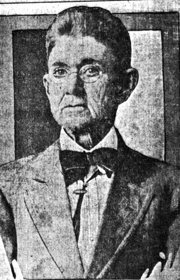 Older white woman dressed as a man with glasses in suit and bow tie