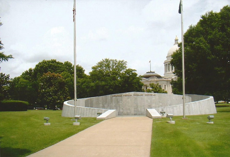 Entrance to memorial wall with curved concrete walls and flags