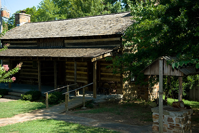 Log cabin wheelchair ramp and nearby covered well and trees