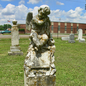 Sleeping angel monument in foreground and other monuments and gravestones in background