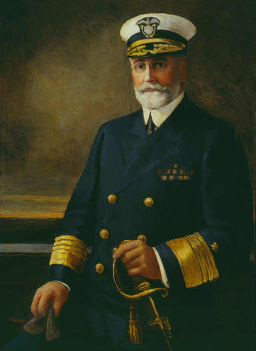 White man in Naval officer's uniform and cap with hand on sword