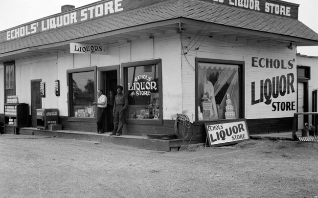 "Echols' Liquor store" on street with a white man and black man standing outside