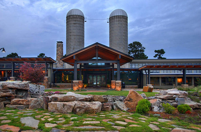 Modern building with covered entrance and walkways and two silos behind it in the background