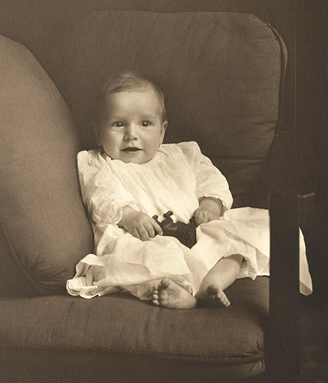 White baby boy with toy leaning against cushions