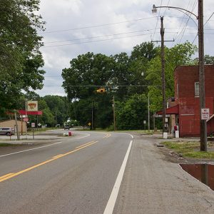 Two-lane road with service station on the left and brick buildings on the right side