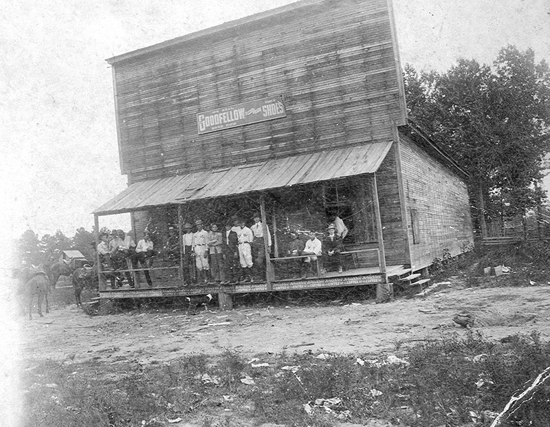 Men standing on porch of wooden building