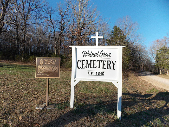 "Walnut Grove Cemetery established 1840" sign with cross and historical marker sign next to dirt road