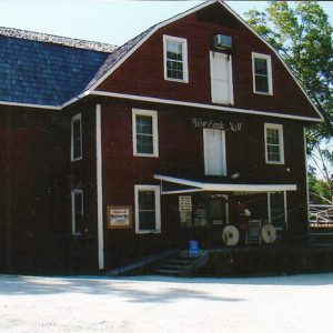 Multistory mill building with red siding and covered entrances